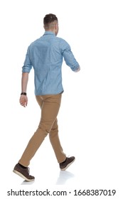 Rear View Of Casual Man Walking While Wearing Blue Shirt On White Studio Background