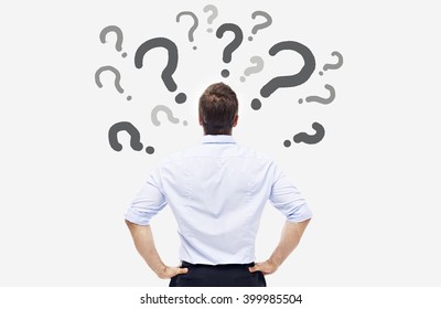 rear view of a caucasian business person looking at the question marks on white board.
