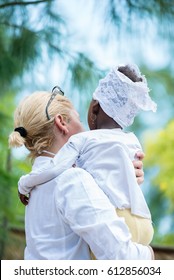 Rear View Of Caucasian Female Doctor Holding African Black Little Girl