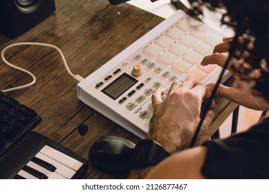 rear view of caucasian man making beats on a midi controller in his home studio, producing electronic music and urban music, composing music and commercial music tracks