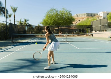 Rear view of a caucasian teen girl playing a tennis game with a friend while exercising and having fun - Powered by Shutterstock