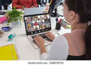 Rear View Of Caucasian Woman Video Conferencing With Coworkers Over Laptop At Office. Unaltered, Meeting, Teamwork, Business, Communication And Technology Concept.