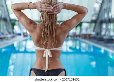 Rear view, charming girl in a swimsuit with a beautiful sports figure standing near the swimming pool and enjoying the rest. - Powered by Shutterstock