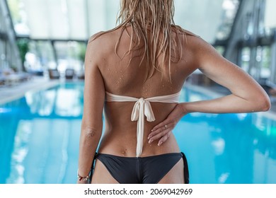 Rear view, charming girl in a swimsuit with a beautiful sports figure standing near the swimming pool and enjoying the rest. - Powered by Shutterstock