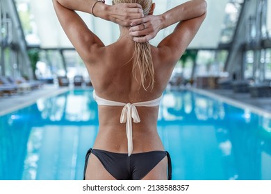 Rear view, charming girl in a swimsuit with a beautiful sports figure standing near the swimming pool and enjoying the rest. - Powered by Shutterstock