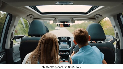 Rear view. Children boy and girl sitting in back seat of car during family trip. Happy family is driving a modern car - Shutterstock ID 2305350575