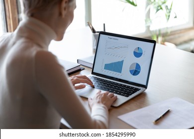 Rear view close up businesswoman working with financial project statistics on laptop, accountant employee analyzing data, graphs charts, report, looking at computer screen, sitting at work desk - Powered by Shutterstock