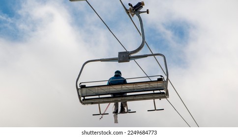 Rear view of a close up of one skier ridding a chairlift up Mount Snow.