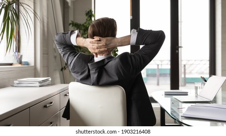 Rear view close up relaxed businessman stretching in comfortable office chair after work done, leaning back, successful confident executive manager leader boss daydreaming, visualizing good future - Shutterstock ID 1903216408