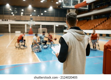 Rear view of coach of basketball watching his team with disabilities playing the game during sports training on the court. - Powered by Shutterstock