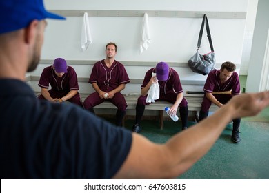 Rear view of coach discussing with baseball team at locker room - Powered by Shutterstock