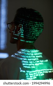 Rear view of computer hacker sitting and reading a computer code reflecting on his back