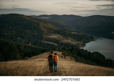 The rear view of a couple explores nature, enjoying the beauty of an evening hike. The lake visible in the background - Powered by Shutterstock