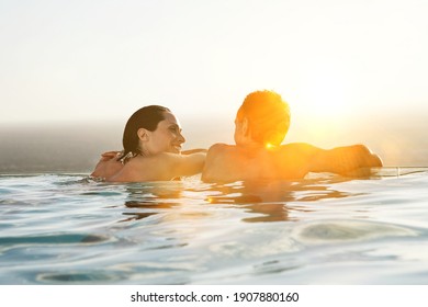 Rear view of couple relaxing in infinity pool at resort - Powered by Shutterstock