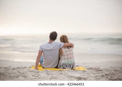 Rear view of couple sitting together on the beach - Powered by Shutterstock