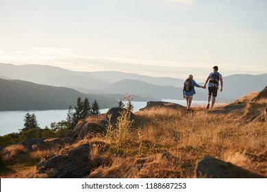 Rear View Of Couple Walking On Top Of Hill On Hike Through Countryside In Lake District UK