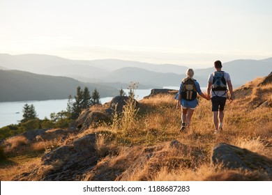 Rear View Of Couple Walking On Top Of Hill On Hike Through Countryside In Lake District UK