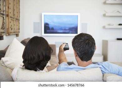 Rear view of couple watching television in living room