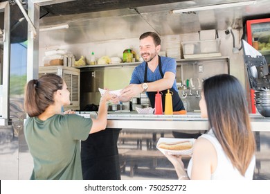 Rear view of a couple of women buying some hot dogs from a food truck - Powered by Shutterstock