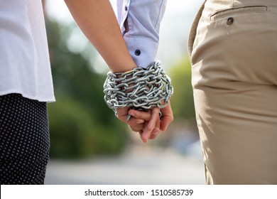 Rear View Of Couple's Hand Tied With Metal Chain At Outdoors