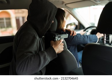 Rear View Of A Criminal Holding At Gunpoint A Young Woman To Steal Her Car Or Commit An Abduction