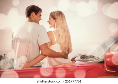 Rear view of cute couple hugging while leaning against their cabriolet - Powered by Shutterstock