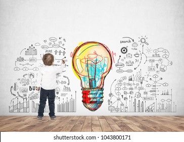 Rear view of a cute little boy wearing a white shirt and dark blue jeans writing or drawing with a marker. A concrete wall background with a good idea sketch - Powered by Shutterstock