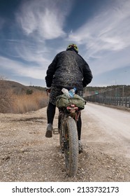 Rear View Of Cyclist Riding On Mud Dirt Road And Completely Muddy Clothes.