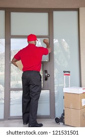 Rear View Of A Delivery Man Knocking On Door