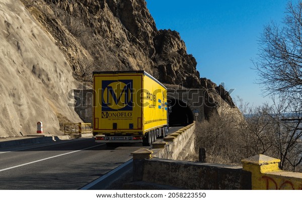 Rear view of delivery truck on the  mountain road,\
at the entrance to the tunnel. Semi-trailer carrying goods on\
highway. Cargo transportation concept. Orsova, Romania, October 10,\
2021