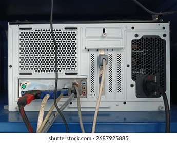 Rear view of a desktop computer showcasing multiple ports, cables, and a power supply. Highlights connectivity, hardware, and a typical tech workspace setup.