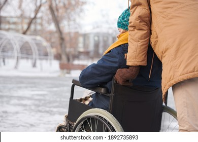 Rear View Of Disabled Woman Walking In The Park In Winter With Her Friend