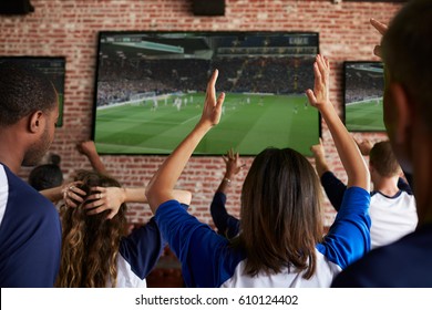 Rear View Of Disappointed Friends Watching Game In Sport Bar