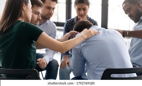 Rear view diverse people comforting frustrated depressed man at meeting, helping overcoming problem, drug or alcohol addiction, sitting in circle at group counselling session, mental healthcare