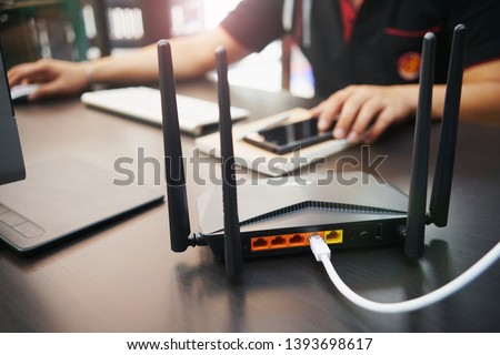 Rear view of Dual Band Router or Wireless AC router with business man using a computer in home office background . Computers and Router wireless broadband Accessories concept                      