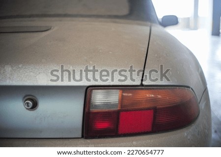 Rear view of dusty old car with indicator light abandoned in the parking lot
