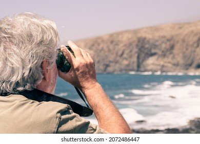 Rear View Of Elderly Man Holding Binoculars Looking At Sea, Mountain. Senior Retired Enjoying Freedom And Knowledge