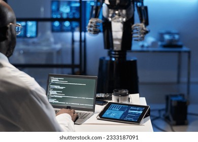 Rear view of engineer typing security codes on laptop to develop robotic industry - Powered by Shutterstock - Get 15% off with code: PIKWIZARD15
