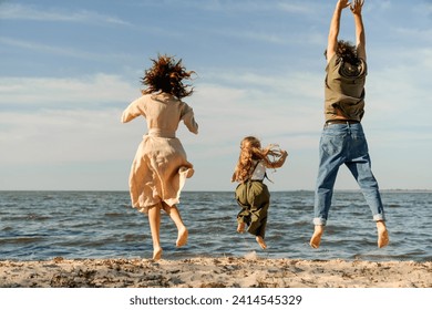 Rear view of family having fun and jumping on the beach, spending vacation on holiday. Daughter kid child with her parents father and mother spending time together outdoors - Powered by Shutterstock