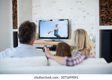 Rear View Of Family Sitting At Home Together Watching Athletics Event On Tv. Sports, Competition, Entertainment And Technology Concept Digital Composite Image.