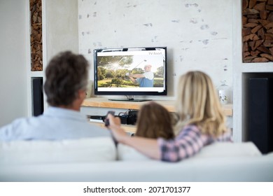 Rear View Of Family Sitting At Home Together Watching Golf Event On Tv. Sports, Competition, Entertainment And Technology Concept Digital Composite Image.