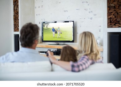 Rear View Of Family Sitting At Home Together Watching Golf Event On Tv. Sports, Competition, Entertainment And Technology Concept Digital Composite Image.