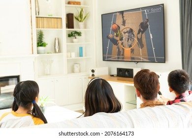 Rear View Of Family Sitting At Home Together Watching Basketball Match On Tv. Sports, Competition, Entertainment And Technology Concept Digital Composite Image.