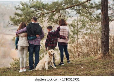 Rear view of family that standing together with their dog outdoors in forest.