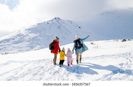 Rear View Of Family With Two Small Children In Winter Nature, Walking In The Snow.