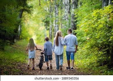 Rear View Of Family Walking Along Autumn Path In A Park Or Forest