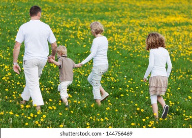 Rear View Of A Family Walking Away Over Grassy Field