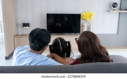 Rear view of family watching tv in living room - Powered by Shutterstock