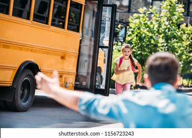 Rear View Of Father With Open Arms Waiting For Adorable Little Daughter While She Running From School Bus