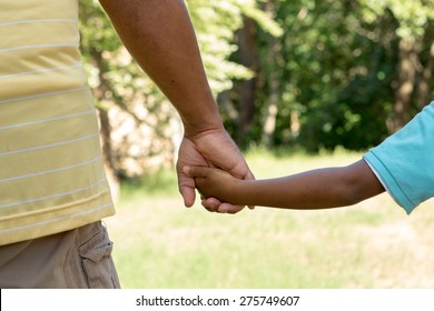 Rear view of father and son holding hands.